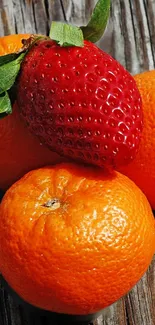 Fresh oranges and a strawberry on rustic wood.