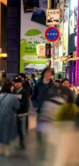 Vibrant city street scene at night with lit signs and bustling crowd.