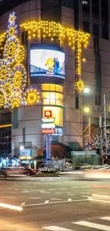 Nighttime city scene with festive Christmas lights decorating a building.