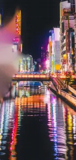 Vibrant neon-lit cityscape reflecting on a calm river at night.