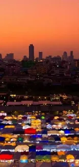 Colorful market tents beneath sunset city skyline.