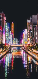 Vibrant cityscape at night with colorful lights reflecting on water.