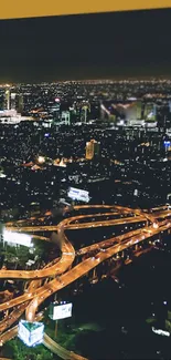 Aerial night view of a vibrant cityscape with illuminated highways.