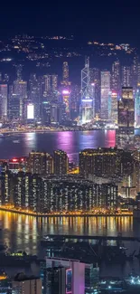 Vibrant city skyline at night with reflections in the water, glowing with lights.