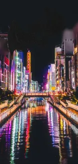 Colorful cityscape at night with vibrant reflections in a water canal.