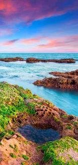 Vibrant coastal sunset with green rocks and colorful skies on a beach.