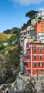 Colorful coastal village on cliffs by the blue sea with vibrant architecture.