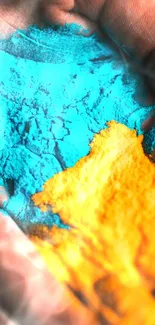 Hand covered in vibrant blue and orange powders on a mobile wallpaper.