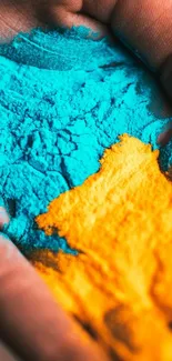 Hand with blue and yellow powder for a vibrant mobile wallpaper design.