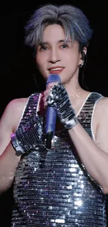 Stylish performer on stage in sequin attire, holding a microphone.