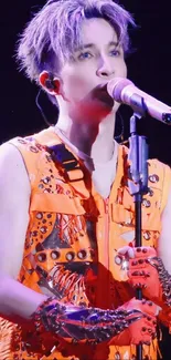 Performer in vibrant orange costume singing onstage.