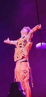 Vibrant performer in orange attire on a purple-lit stage.