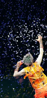 Performer in orange outfit surrounded by confetti on stage.