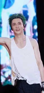 Performer in white tank top on vibrant concert stage.