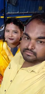 Vibrant couple in yellow attire, smiling warmly.