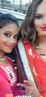 Two women in traditional attire with vibrant smiles on a festive occasion.