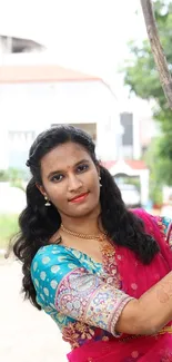 Woman in vibrant traditional attire outdoors.