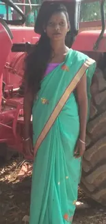 Woman in green sari beside red tractor, rural setting.