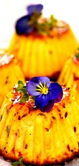 Golden cupcakes with purple flowers on top.