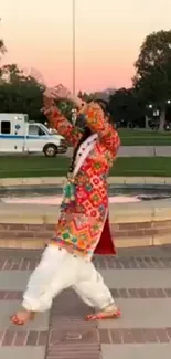 Dancer in colorful traditional attire performing in an outdoor setting.