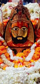 Deity surrounded by vibrant orange and white flowers.