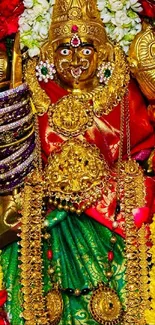 Image of a deity with gold jewelry and colorful floral garlands.