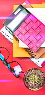 Colorful study essentials with calculator and cactus on red background.