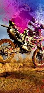 Motocross rider jumps with vibrant pink and blue paint splashes.