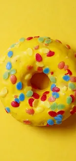 Vibrant yellow donut with colorful sprinkles on a matching background.
