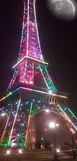 Eiffel Tower with vibrant neon lights under moonlight.