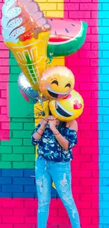 Bright emoji balloons against colorful brick wall background.