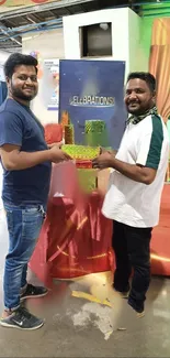 Two people holding colorful gifts at a vibrant celebration event indoors.