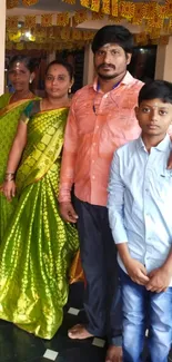 Family poses in vibrant attire with festive decorations in the background.