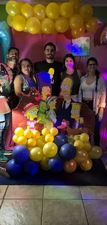 People posing with colorful balloons and cartoon cutouts at a festive event.