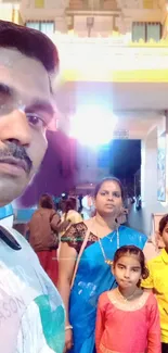 Family in traditional attire at temple during evening.