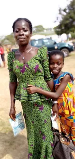 Mother and child in colorful attire in an outdoor setting.