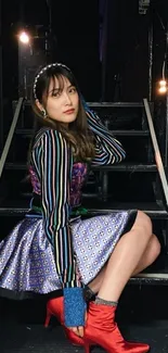 Fashionable woman sitting on stairs with vibrant outfit.