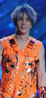 Person in a vibrant orange outfit on stage.