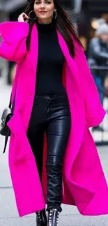 Fashionable woman in a vibrant pink coat and black ensemble on the street.