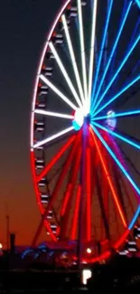 Vibrant Ferris wheel with red and blue lights at sunset.