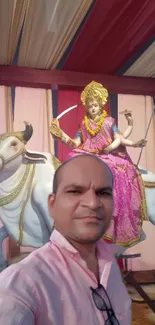 Man posing with festival statue in vibrant colors.