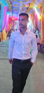 Man walking in a colorful, fabric-draped festive walkway.