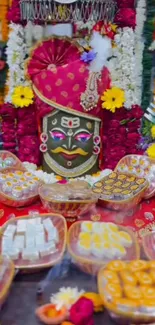 Festive Hindu deity surrounded by vibrant flowers and sweets.