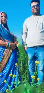 Couple in vibrant attire standing in a sunlit field.