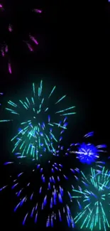 Vibrant fireworks illuminate a dark night sky with blue and green bursts.