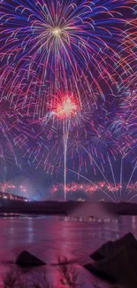 Stunning fireworks display over water at night with vibrant magenta hues.