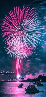 Pink fireworks over a harbor at night with boats and a bridge.