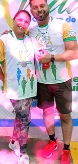 Two athletes pose under pink lights at a fitness event.