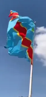 Vibrant flag waving on a clear, blue sky background with white clouds.