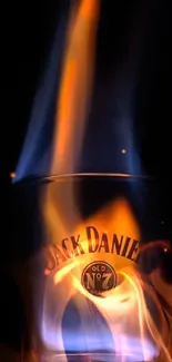 A glowing flame emerging from a whiskey glass, set against a dark background.